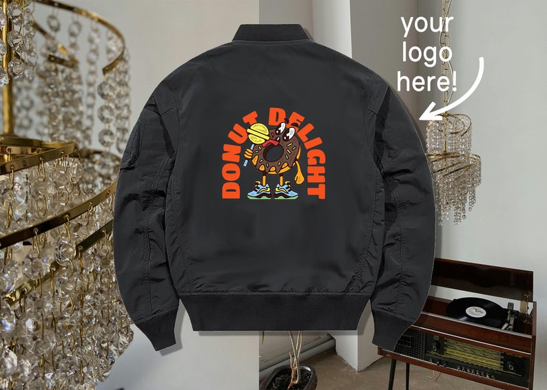 May include: Black bomber jacket with a donut character graphic on the back. The graphic says "Donut Delight" and features a donut with eyes, a mouth, and arms holding a lollipop.