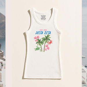 Peut inclure: Débardeur blanc côtelé avec un motif tropical représentant des palmiers, des fleurs roses et un crabe. Le texte "EST. 1902 DELTA ZETA" est imprimé en bleu et rose. Le haut porte le logo "Spikes and Seams".