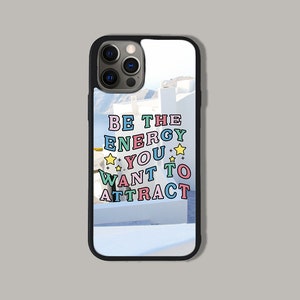 May include: A black phone case with a white background and the text "BE THE ENERGY YOU WANT TO ATTRACT" in colourful letters with yellow stars.