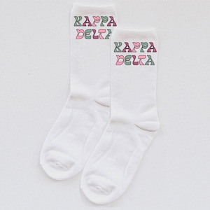 Puede incluir: Un par de calcetines blancos con las palabras "Kappa Delta" impresas en letras rosas, verdes y moradas.