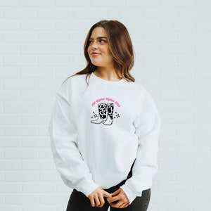 May include: White sweatshirt with a pink and black graphic of cowboy boots with the text "I'd Rather Be In Boots" printed on the front.