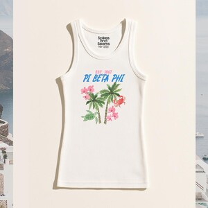 Puede incluir: Camiseta sin mangas blanca acanalada con el texto "Spikes and Seams" en el escote. La camiseta presenta un gráfico de palmeras, flores rosas y un cangrejo, con el texto "PI BETA PHI EST. 1867".