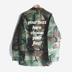 May include: A camouflage green utility jacket with a white text overlay that says "your text here, choose your font!"