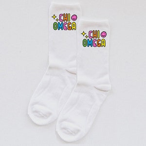May include: A pair of white socks with a colourful "CHI OMEGA" graphic and a smiley face on each sock.