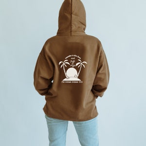 May include: A brown hooded sweatshirt with a white graphic on the back. The graphic features palm trees, a sunset, and the text "remember to slow down and take it easy". Below the graphic is the text "Phi Sigma Sigma 1913".