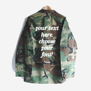 Puede incluir: Una chaqueta utilitaria de color verde camuflaje con un texto blanco superpuesto que dice "your text here, choose your font!"