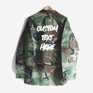 May include: A camouflage green jacket with the words "CUSTOM TEXT HERE" written in white on the back.