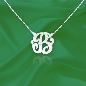 May include: A silver necklace with a delicate chain and a large, ornate letter 'B' pendant.