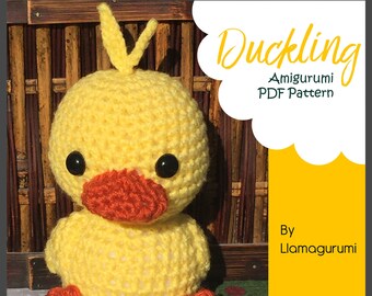May include: A yellow crocheted duckling amigurumi pattern. The duckling is sitting on a green surface with a wooden background. The text "Duckling Amigurumi PDF Pattern" is in a white cloud on a yellow background. The text "By Llamagurumi" is on a yellow background.