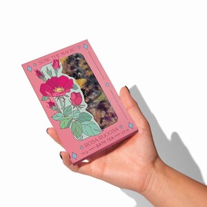 May include: A pink box with a floral design and the text "Sow the Magic" and "Rosa Rugosa - Bath Tea - 78 g - 2.8 oz". The box contains dried rose petals.