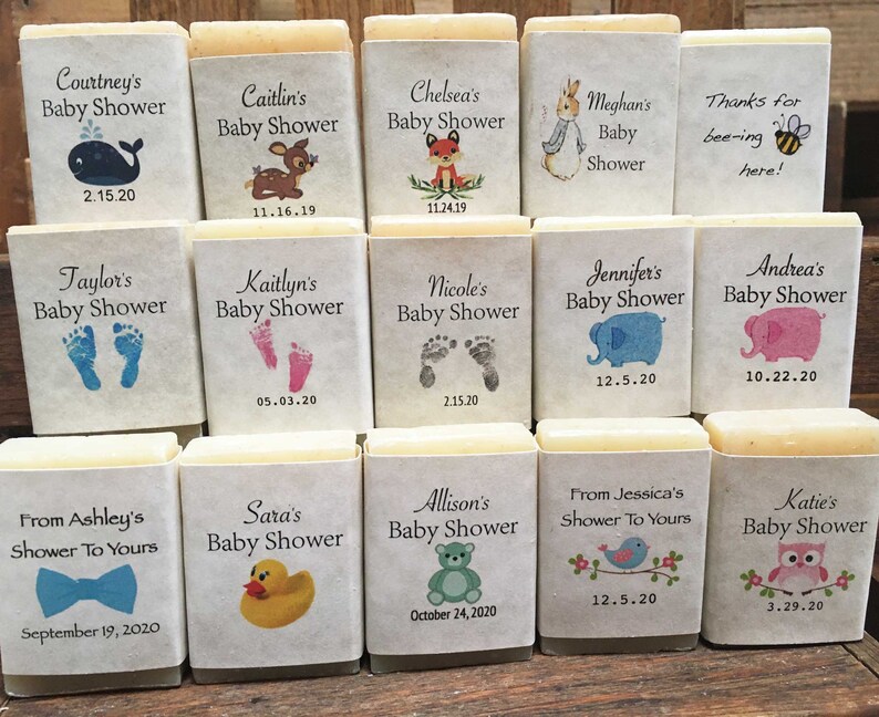Pode incluir: Doze pequenas barras retangulares de sabonete com v&aacute;rios temas de ch&aacute; de beb&ecirc;. Cada barra tem um design e um texto diferente, incluindo animais, pegadas e la&ccedil;os. O texto inclui nomes, datas e frases como "Ch&aacute; de Beb&ecirc;" e "Obrigado por estar aqui!"