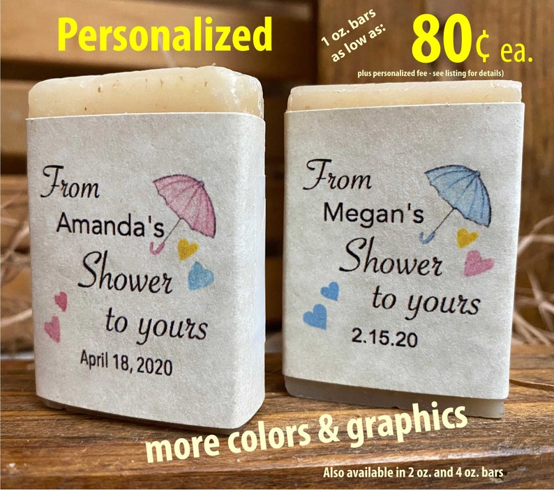 Pode incluir: Dois sabonetes personalizados de 1 on&ccedil;a com um tema de chuveiro. Os sabonetes s&atilde;o embrulhados em papel branco com um design de guarda-chuva rosa e azul. O texto nos sabonetes diz "From Amanda's Shower to yours April 18, 2020" e "From Megan's Shower to yours 2.15.20".