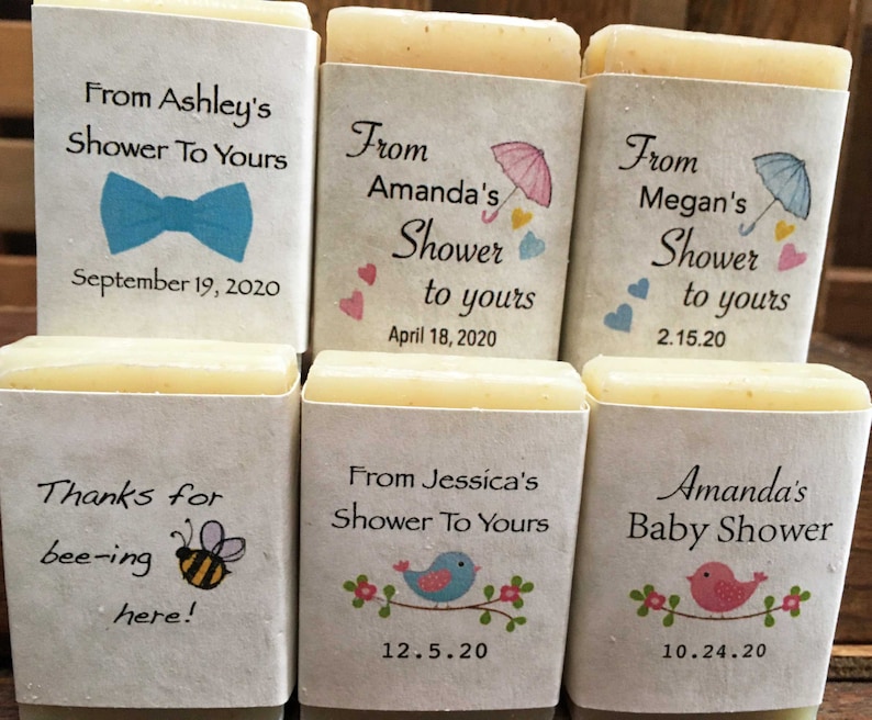 Pode incluir: Seis pequenas barras de sabonete branco com etiquetas impressas. As etiquetas t&ecirc;m diferentes designs e textos, incluindo "From Ashley's Shower To Yours", "From Amanda's Shower to yours", "From Megan's Shower to yours", "Thanks for bee-ing here!", "From Jessica's Shower To Yours", e "Amanda's Baby Shower".
