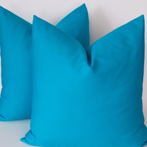 May include: Two turquoise blue throw pillows with a square shape and a smooth fabric texture.