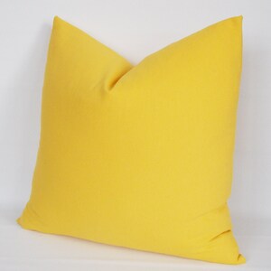 May include: A bright yellow throw pillow with a square shape and a soft, smooth texture.
