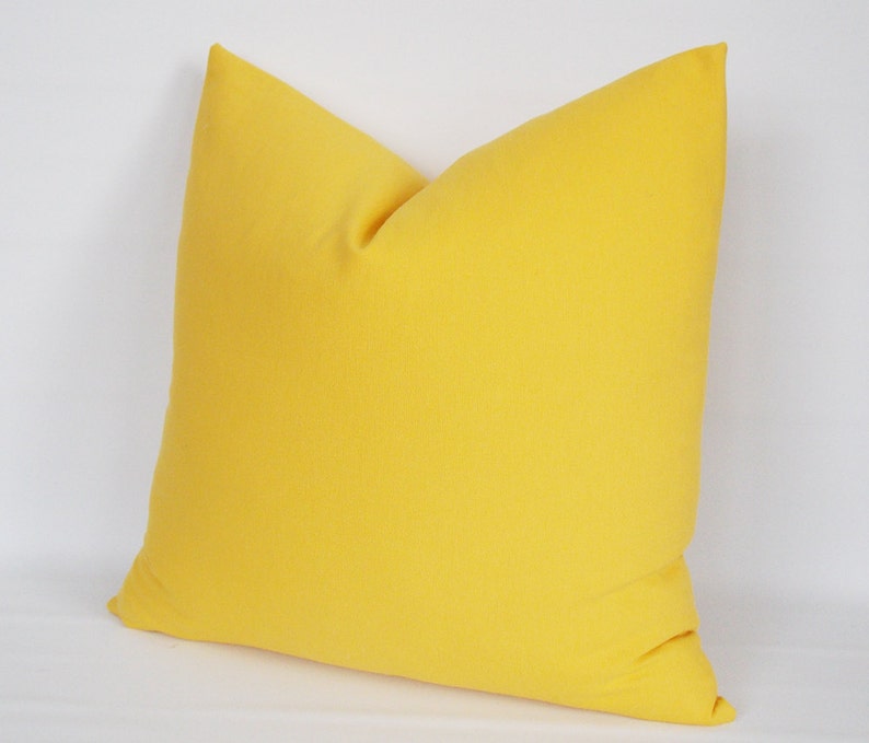 May include: A bright yellow throw pillow with a square shape and a soft, smooth texture.