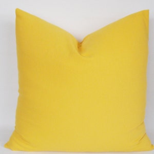 May include: A solid yellow throw pillow with a square shape.