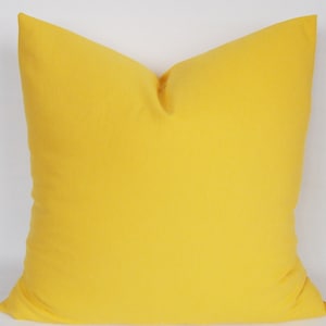 May include: A solid yellow throw pillow with a square shape.