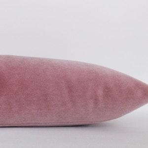 May include: A soft, dusty rose velvet pillow with a smooth, even texture.