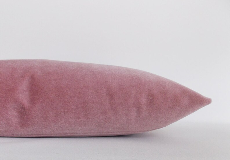 May include: A soft, dusty rose velvet pillow with a smooth, even texture.