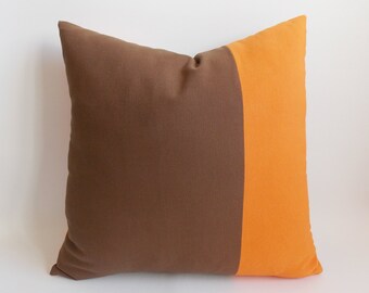 May include: A brown and orange throw pillow with a vertical stripe of orange down the center.