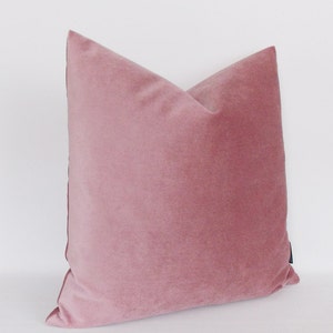 May include: A soft, dusty rose velvet pillow with a subtle sheen. The pillow is square and has a simple, elegant design.