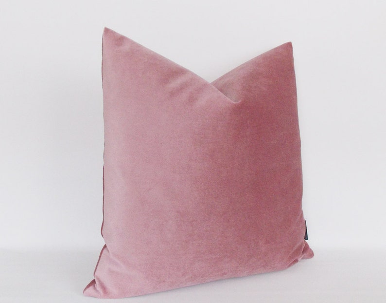 May include: A soft, dusty rose velvet pillow with a subtle sheen. The pillow is square and has a simple, elegant design.