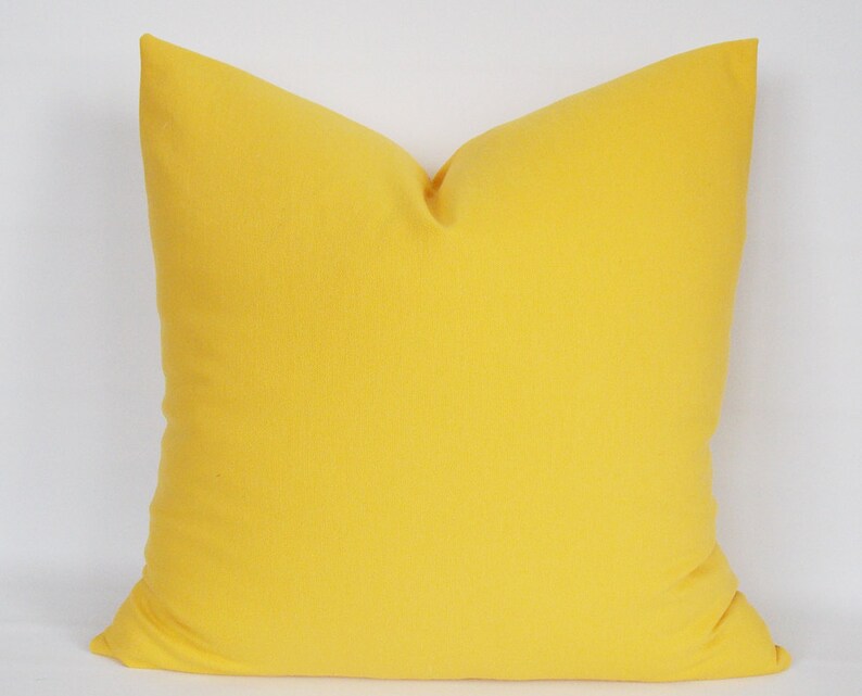 May include: A bright yellow throw pillow with a square shape and a soft, smooth texture.