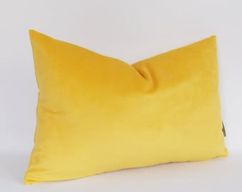 May include: A bright yellow velvet pillow with a smooth, soft texture. The pillow is rectangular and has a simple, modern design.