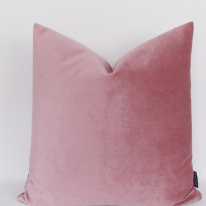 May include: A soft, blush pink velvet pillow cover. The pillow is square and has a simple, elegant design.