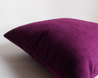May include: A deep purple velvet pillow with a subtle textured pattern. The pillow is shown lying on a white surface.
