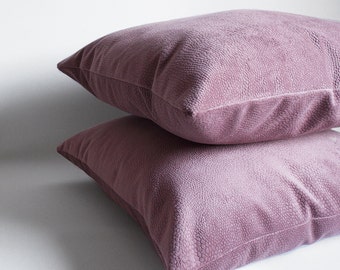May include: Two soft, plush pillows in a dusty rose color. The pillows are stacked on top of each other, with the top pillow slightly overlapping the bottom pillow.