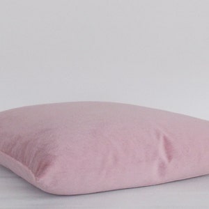 May include: A soft, blush pink throw pillow with a smooth, velvety texture.