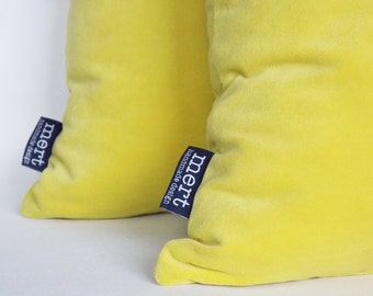 May include: Two yellow velvet pillow covers with a blue label that says "mert handmade design".