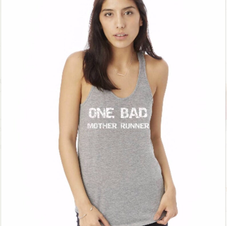Puede incluir: Camiseta gris de tirantes con el texto "ONE BAD MOTHER RUNNER" en blanco.