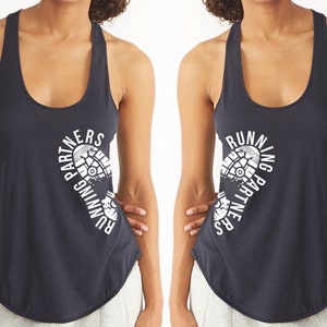 Puede incluir: Dos camisetas de tirantes negras con un gráfico blanco de una huella de zapato para correr y el texto "Running Partners" a cada lado.