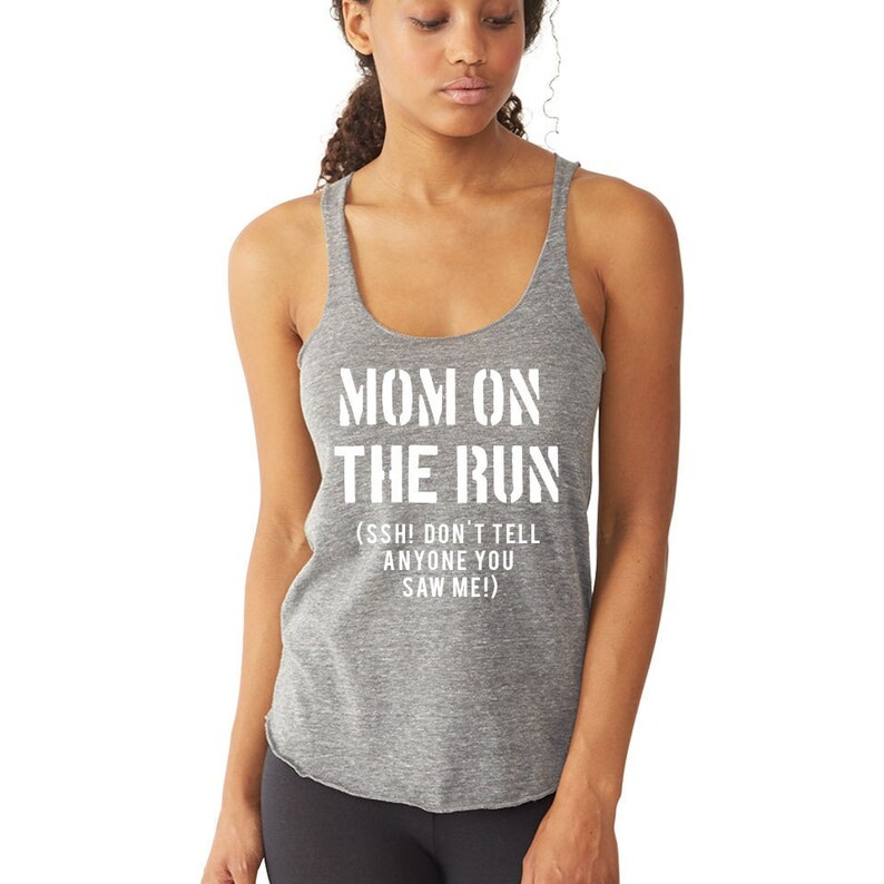 Puede incluir: Camiseta de tirantes gris con el texto "MOM ON THE RUN (SSH! DON'T TELL ANYONE YOU SAW ME!)" impreso en blanco.