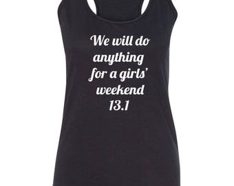 May include: Dark gray racerback tank top with white text that reads "We will do anything for a girls' weekend 13.1". The tank top has a scoop neck and is made of a soft material. Ideal for running or casual wear.
