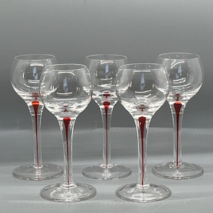 May include: A set of five clear glass stemmed glasses, each featuring a distinct red accent line running vertically through the center of the stem, extending from the base of the bowl down to the circular foot of the glass.