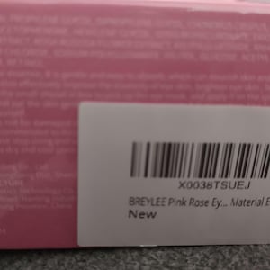 May include: A white label with black barcode and text that reads "X0038TSUEJ BREYLEE Pink Rose Ey... Material Extraction New". The label is attached to a pink box with white text.