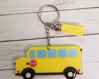 Puede incluir: Llavero de autobús escolar amarillo con una señal de stop roja y un borla amarilla.