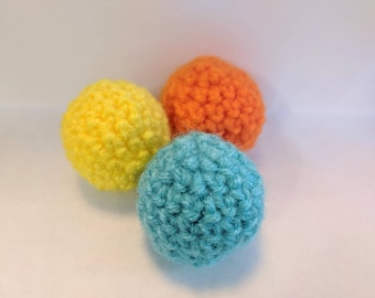 May include: Three crocheted balls in yellow, orange, and blue.