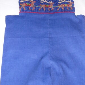 May include: Blue corduroy overall shorts with a red trim and embroidered reindeer design.