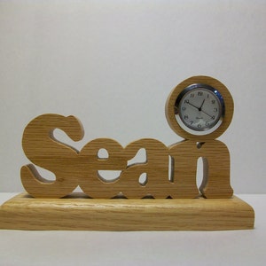 May include: A wooden nameplate with the name "Sean" carved into it. A small clock is attached to the nameplate.