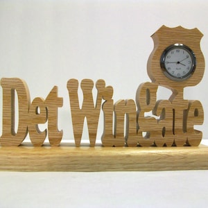 May include: Wooden desk sign with the text "Det Winsgate" and a small clock in the shape of a police badge.