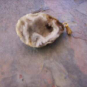 May include: A white agate pendant with a natural crystal formation and a gold-toned metal bail.
