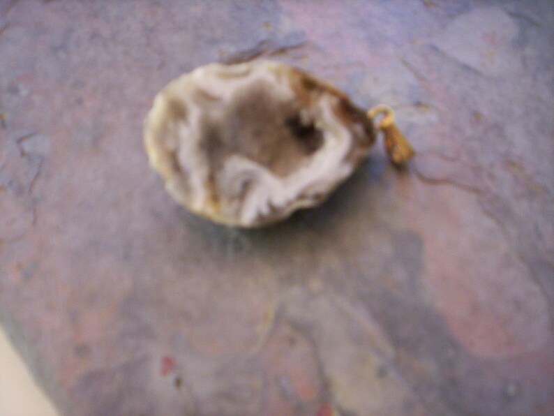 May include: A white agate pendant with a natural crystal formation and a gold-toned metal bail.