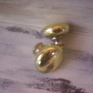 Könnte beinhalten: Zwei vergoldete Türknauf mit runder Form. Die Knäufe sind an einem Metallschaft befestigt.