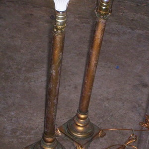 May include: Two antique brass floor lamps with white light bulbs. The lamps have a decorative design on the base and a simple, elegant design.