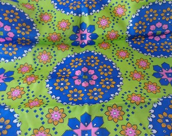 May include: A vibrant textile featuring a repeating floral pattern. The design incorporates blue, pink, and yellow flowers set against a bright green background. The fabric has a geometric arrangement of shapes.
